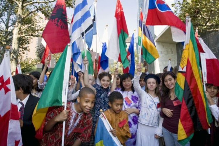 Cheerful young students in their traditional dress proudly waive their national flags during the Peace Bell ceremony of the observance of the International Day of Peace: 