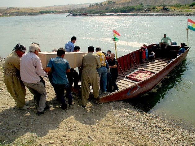 A group of Kurdish mourners bound for Syria board on the Iraqi shore. Credit: Karlos Zurutuza/IPS.