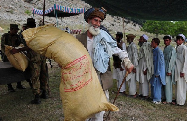 An elderly displaced man carries a sack of rations on his shoulder. The Pakistan Army has distributed 30,000 ration packs of 110 kg each. Credit: Ashfaq Yusufzai/IPS