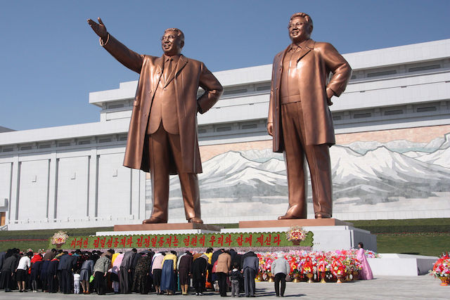 North Koreans bowing to the statues of Kim Il-sung and Kim Jong-il / Wikimedia Commons