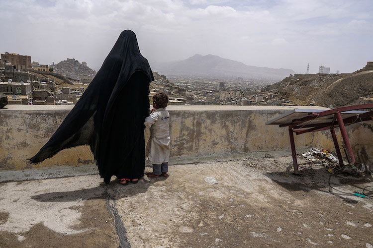 An internally displaced woman and her daughter look over the city of Sana’a, Yemen, from the roof of this dilapidated building they call their new home. Photo: Giles Clarke/UN OCHA