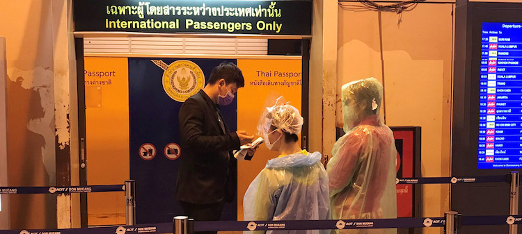 Photo: Passengers wearing face masks and disposable ponchos get their passports checked at Don Mueang International Airport in Bangkok, Thailand. UN News/Jing Zhang