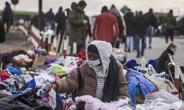 Photo: A woman rummages through a pile of clothes at the Polish border as migrants from Africa, the Middle East and India flee to Poland and other neighbouring countries. Source: NEW FRAME | Wojtek Radwanski