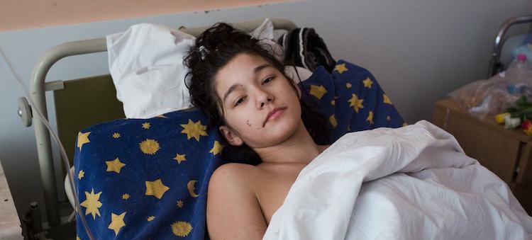 Photo: An injured girl rests in a medical ward in Kyiv, Ukraine, after her car was shelled. © WHO/Anastasia Vlasova